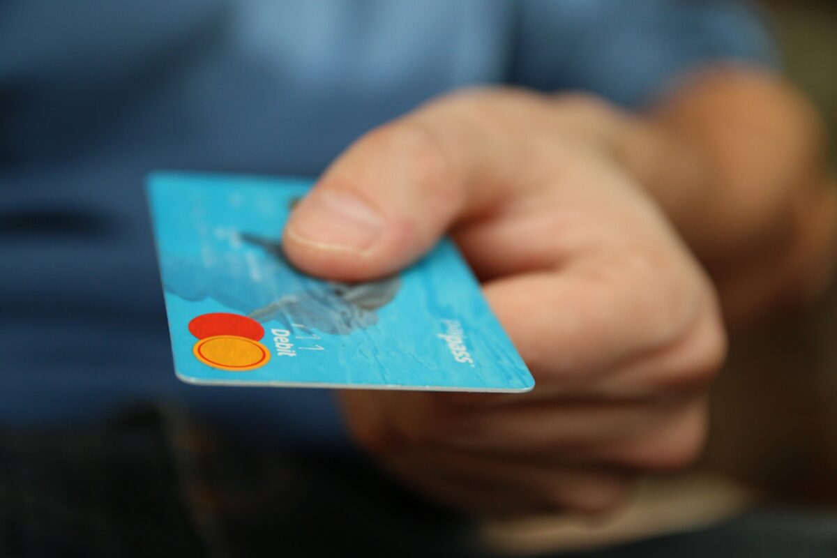 Symbolbild SEO-Content-kaufen: Hand reicht Kreditkarte hin